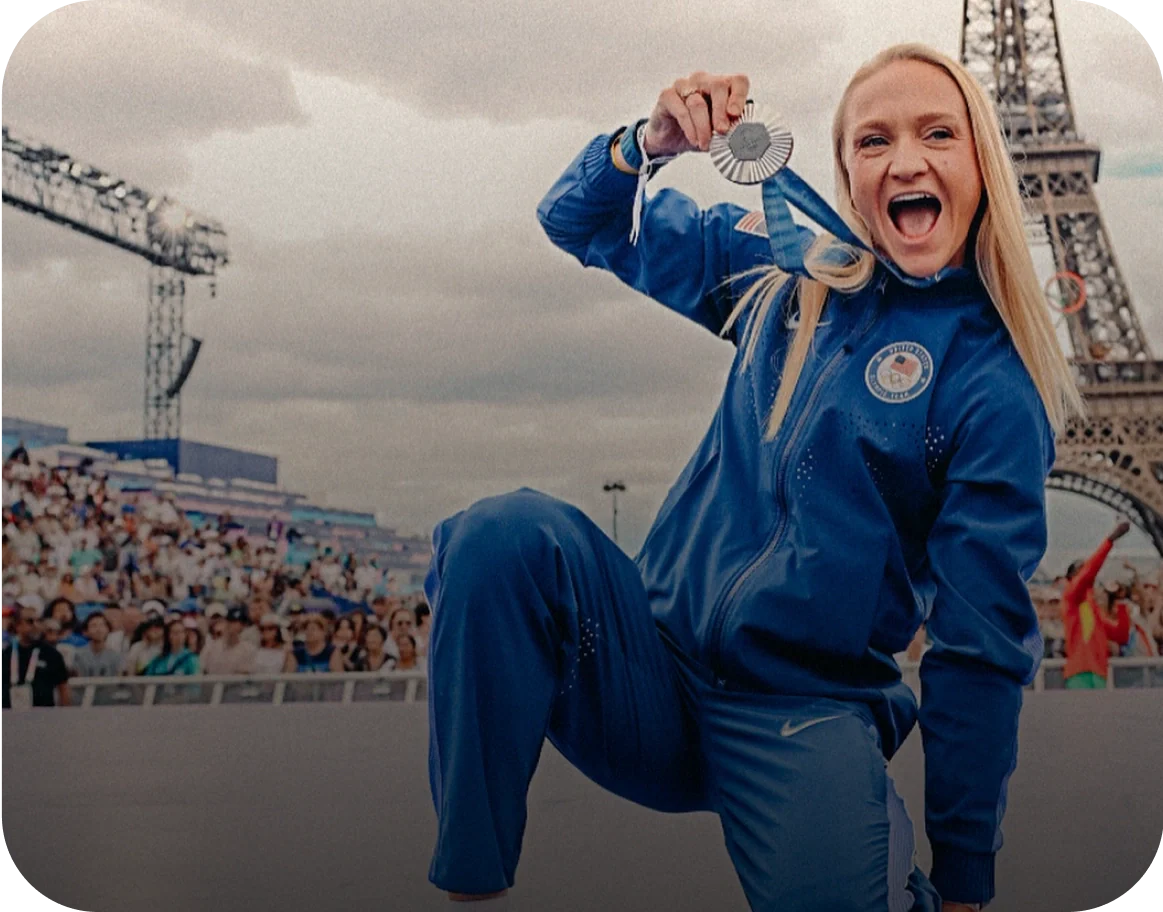 Photo of a woman celebrating with a medal in front of the Eiffel Tower, labeled as Sarah Bacon, Olympian, Silver Medalist, 3x World Silver Medalist, 5x NCAA Champion.